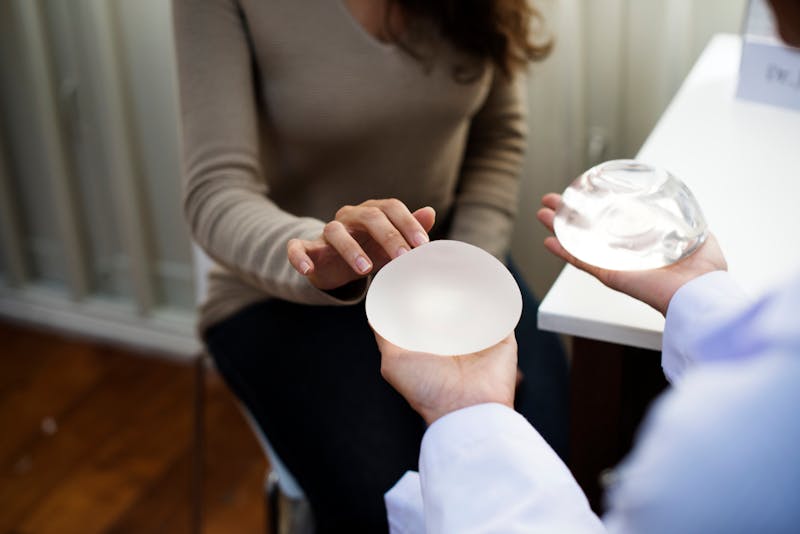 Doctor showing woman breast implants